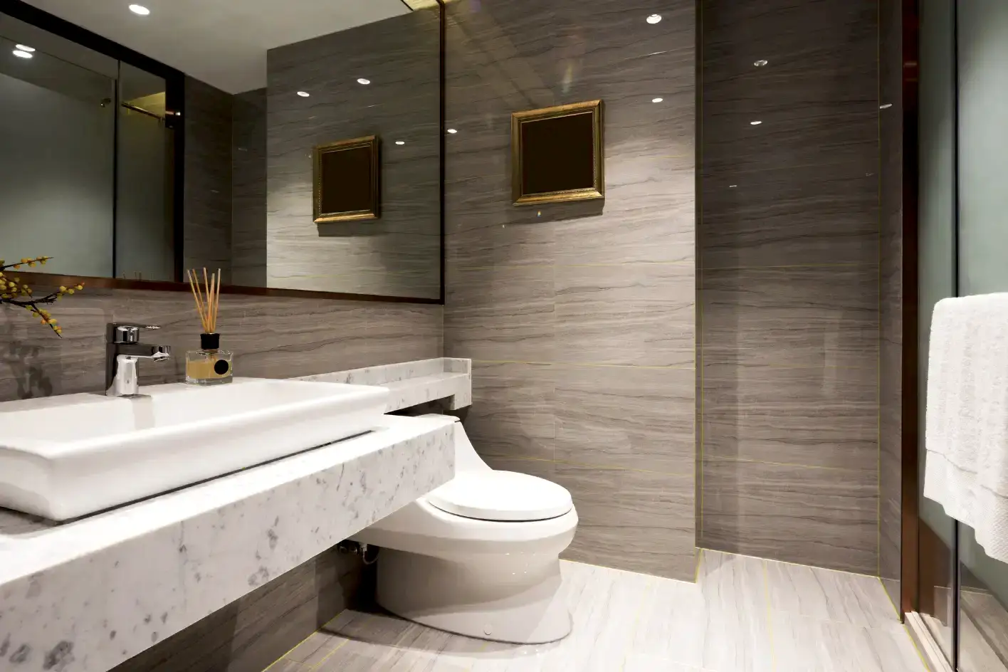 Mermer tezgahlı, gold detaylı gri lüks banyo tasarımı.