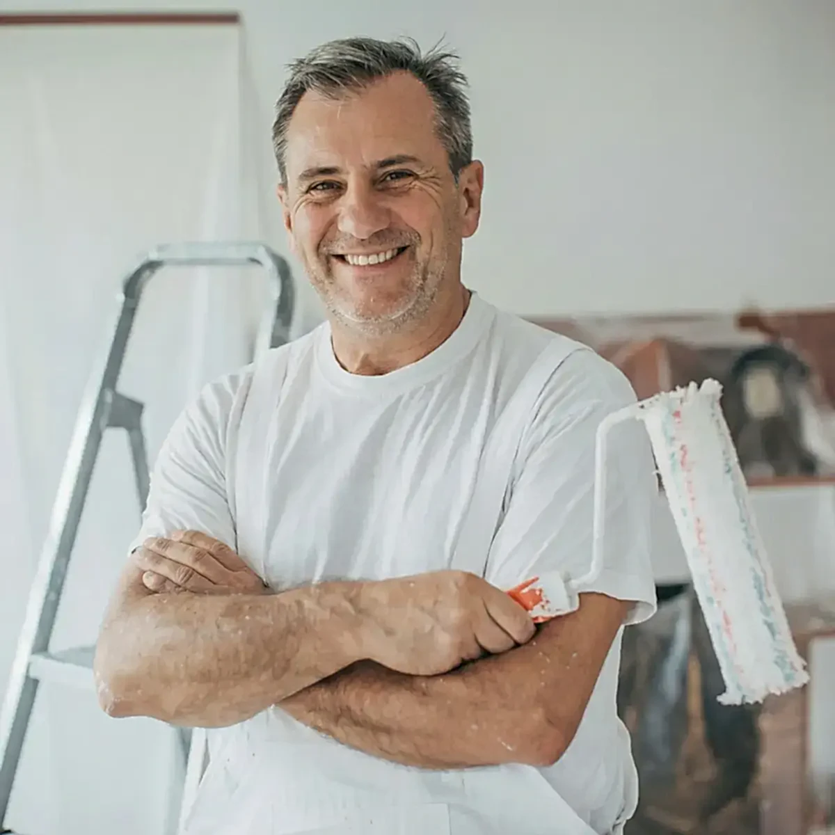 Elinde rulo fırça tutan, beyaz tulumlu profesyonel boya badana ustası.