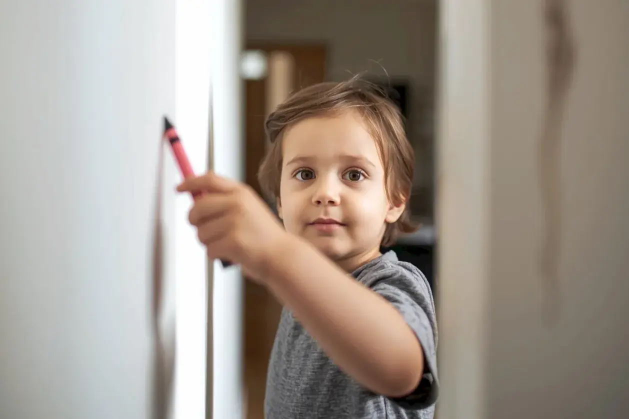 Elinde boya kalemi olan çocuk ve temiz duvar