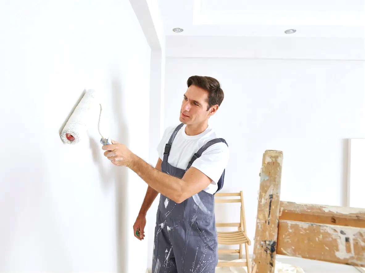 İç mekan tadilatında rulo fırça ile beyaz duvarı boyayan profesyonel boya badana ustası