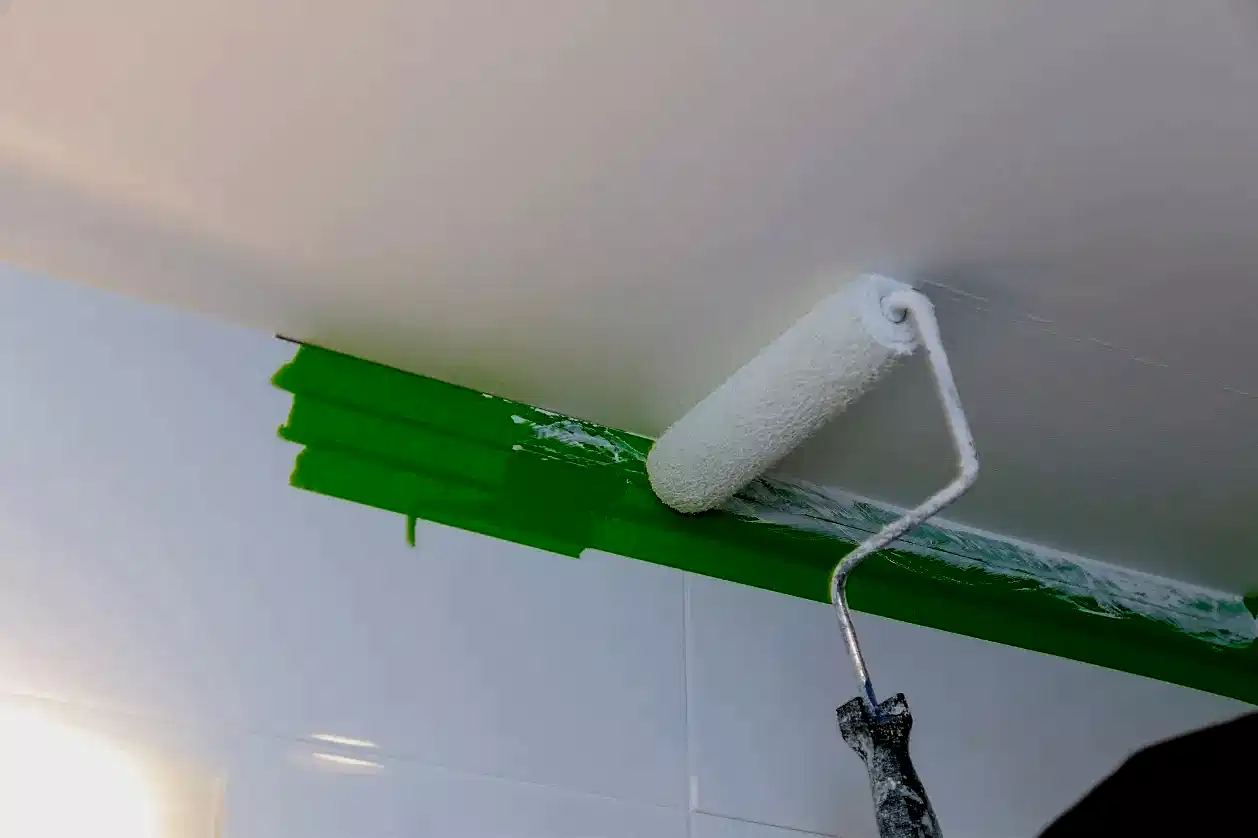 Elinde rulo ile tavanı pürüzsüz boyayan usta